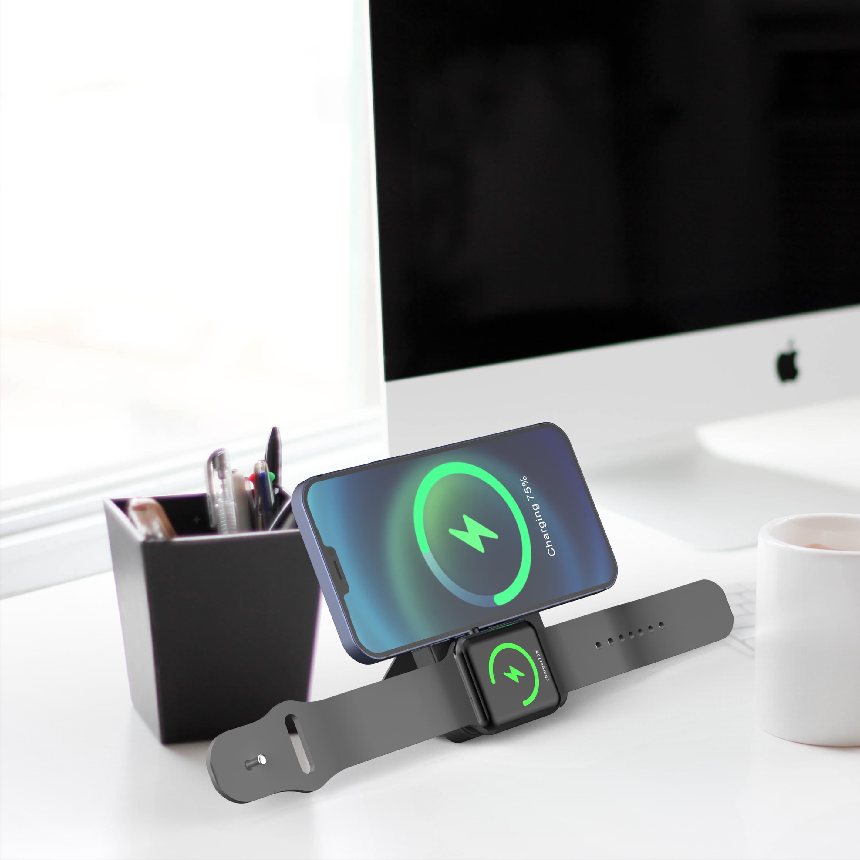 Smartphone and smartwatch charging on a wireless stand on a white desk with a computer.